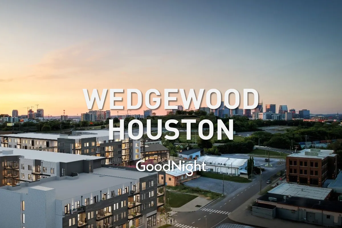 An exterior shot of modern apartment buildings set against the Nashville city skyline at sunset. The image conveys a contemporary urban lifestyle, with hints of community and central location.