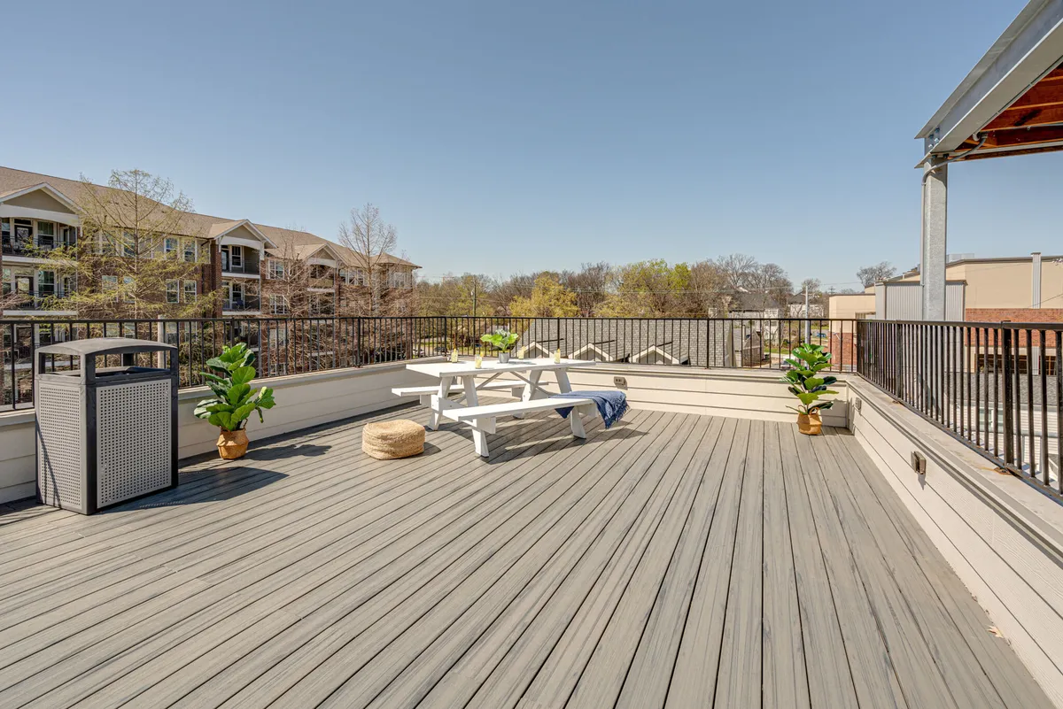 An exterior shot showcasing an uncovered parking lot with a picnic table, planters, and a trash bin. The setting highlights accessible parking as well as a casual outdoor space for relaxing or gathering.