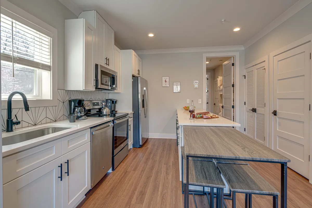 A modern kitchen displays stainless steel appliances, a kitchen island at the center, and streamlined cabinetry. The space looks organized, functional, and ready for group use, with a warm, family-friendly atmosphere.